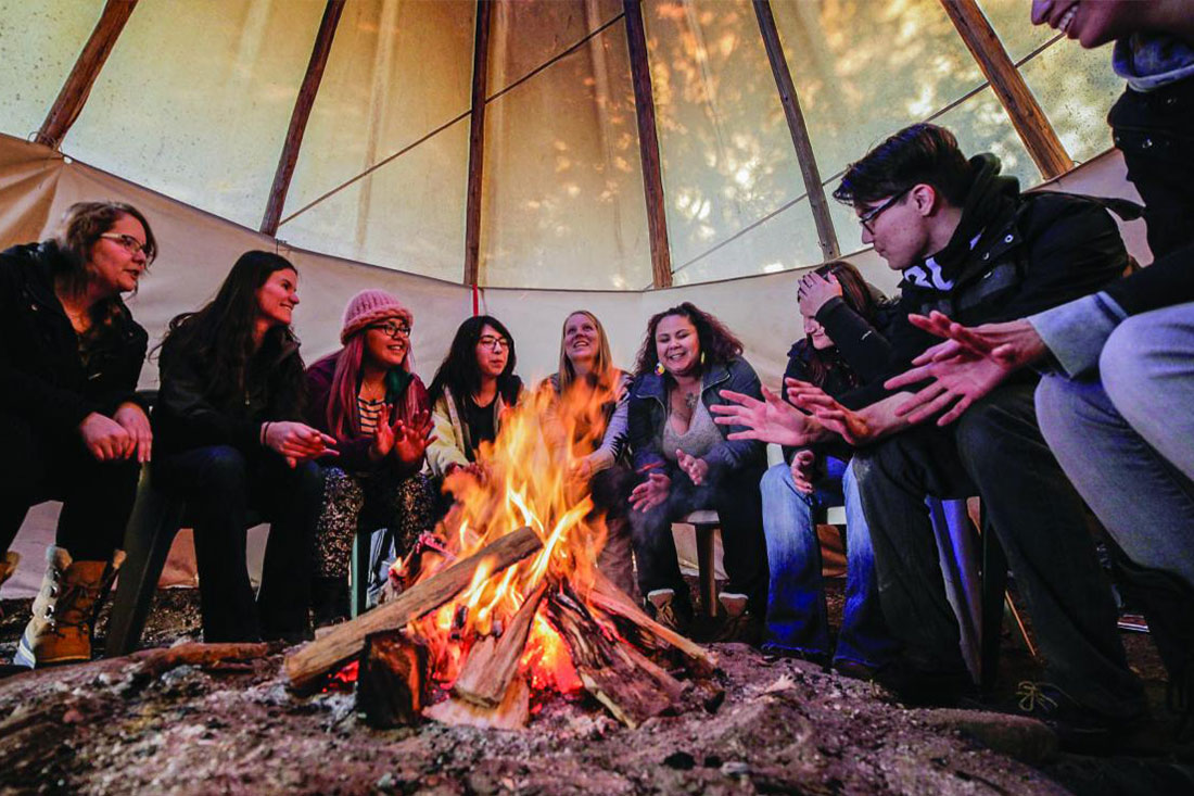 Sitting around a fire inside a teepee